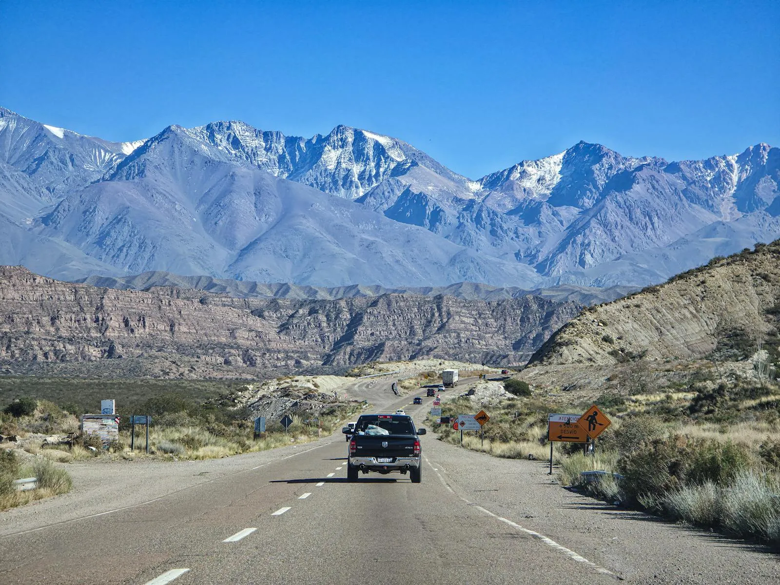 Mountain road winding through the Argentine Andes with dramatic peaks and open landscape