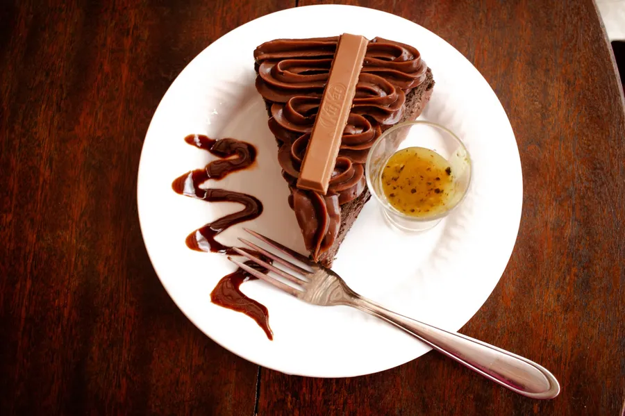 Slice of Sachertorte with dark chocolate glaze and whipped cream