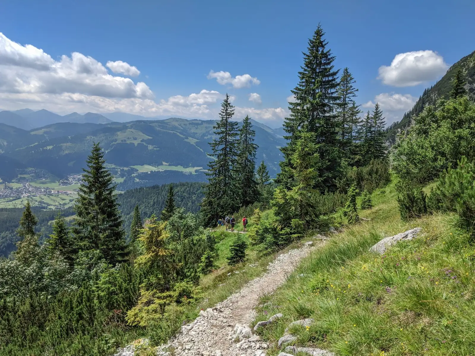 Hikers on an Austrian alpine trail with panoramic peaks behind