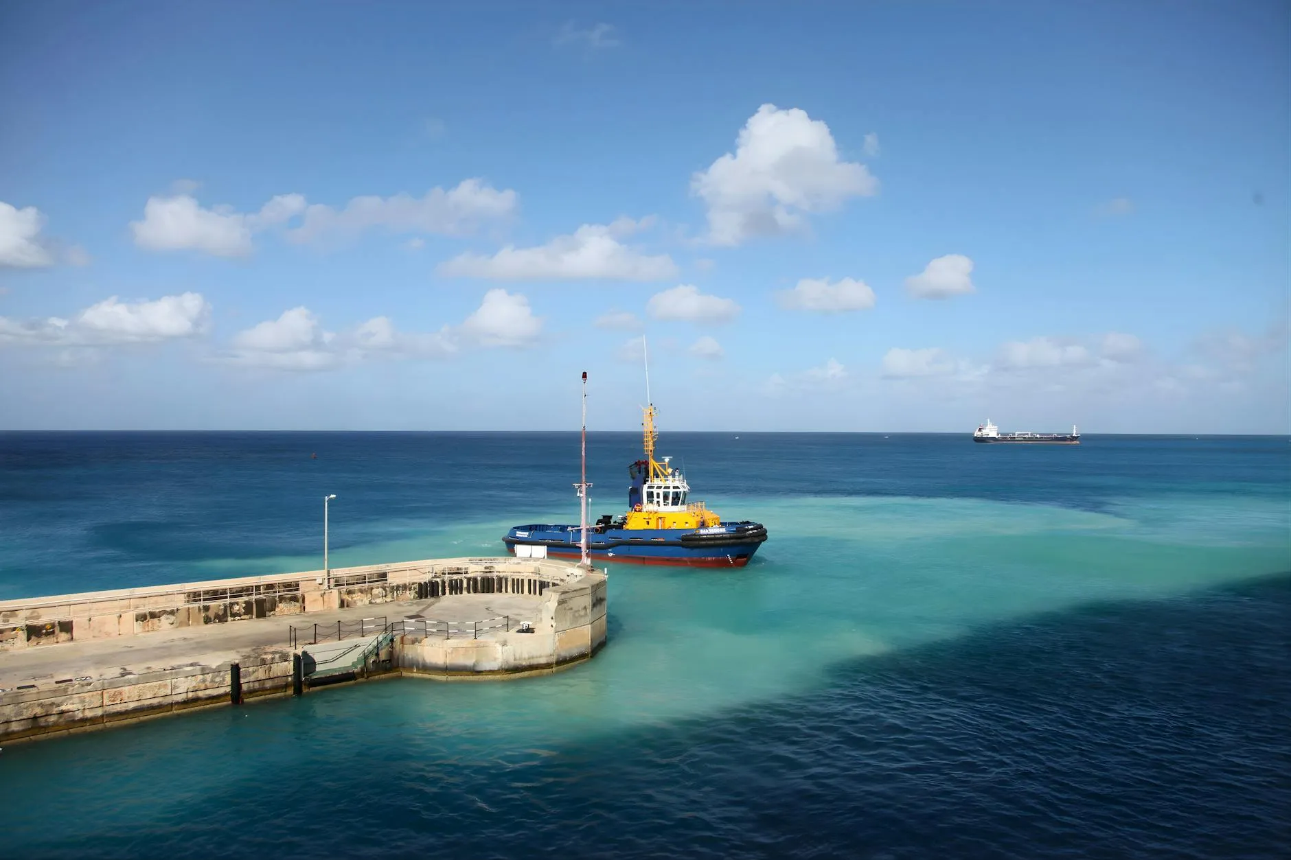 A vibrant tugboat by the dock in clear blue seas under a bright sky, ideal for travel themes.
