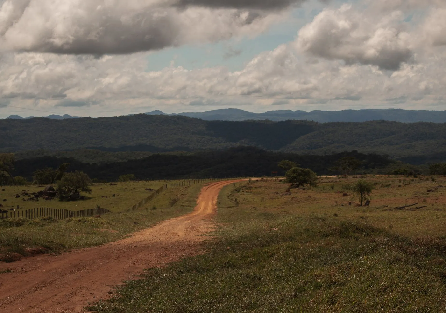 Explore the scenic rural landscape of Bonito, Brazil with this dirt road view leading through lush fields and rolling hills.
