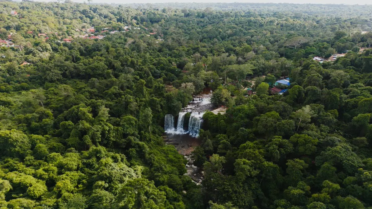 Stunning aerial view of a waterfall surrounded by dense forest in Popel, Siem Reap, Cambodia.
