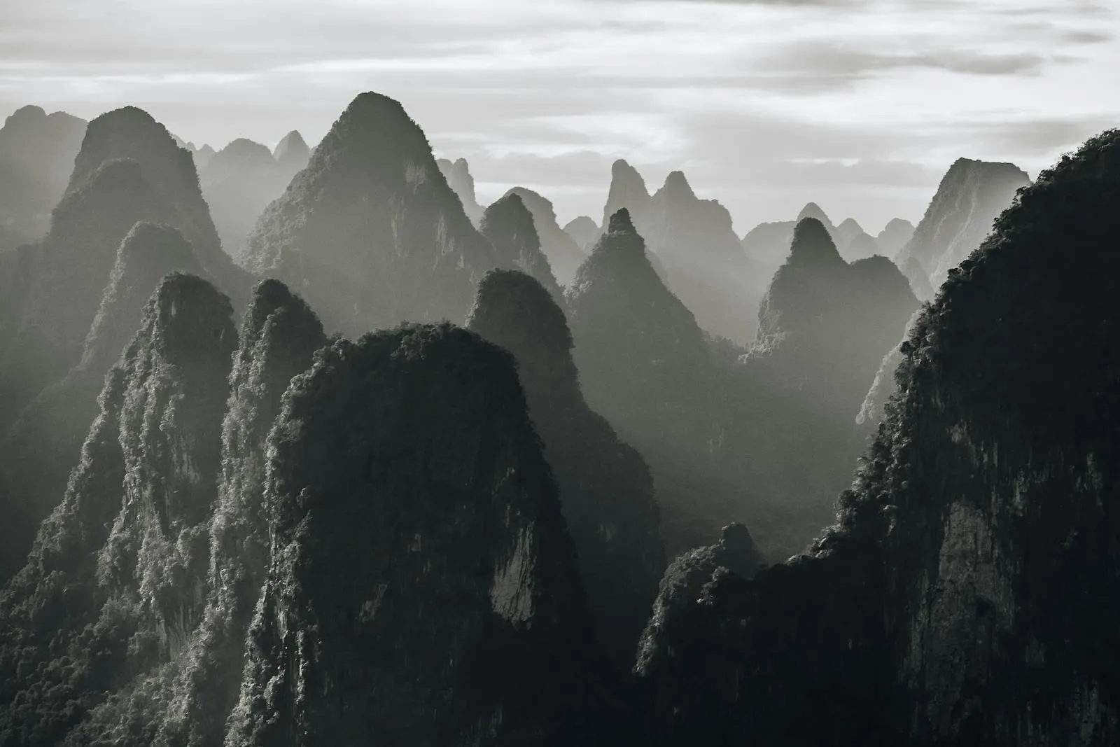 Hiker on a mountain trail with dramatic karst peaks and misty valleys below
