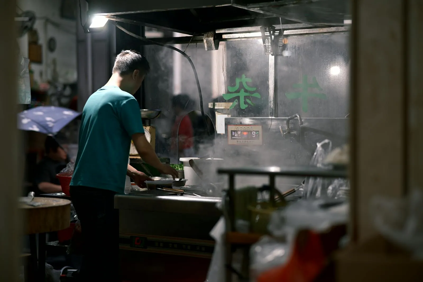 Street vendor preparing hand-pulled noodles in a steamy Chinese food market