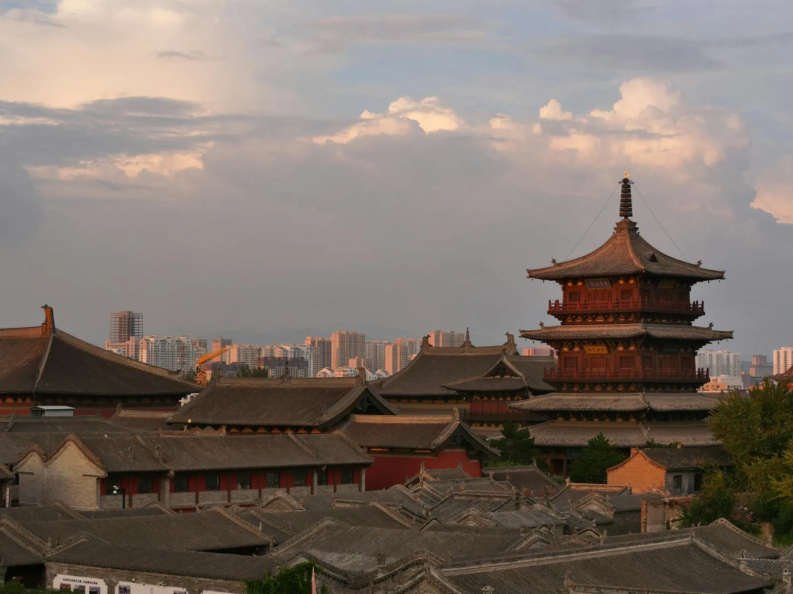 Sunset over traditional Chinese rooftops with pagoda silhouette