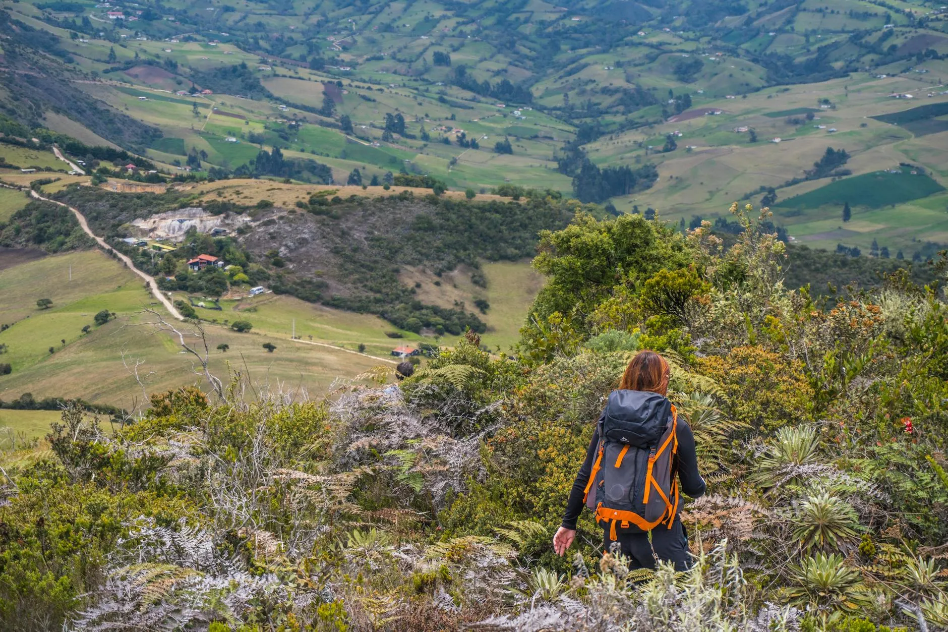Woman hiking with a backpack in the lush landscapes of Guatavita, Colombia, during summer.