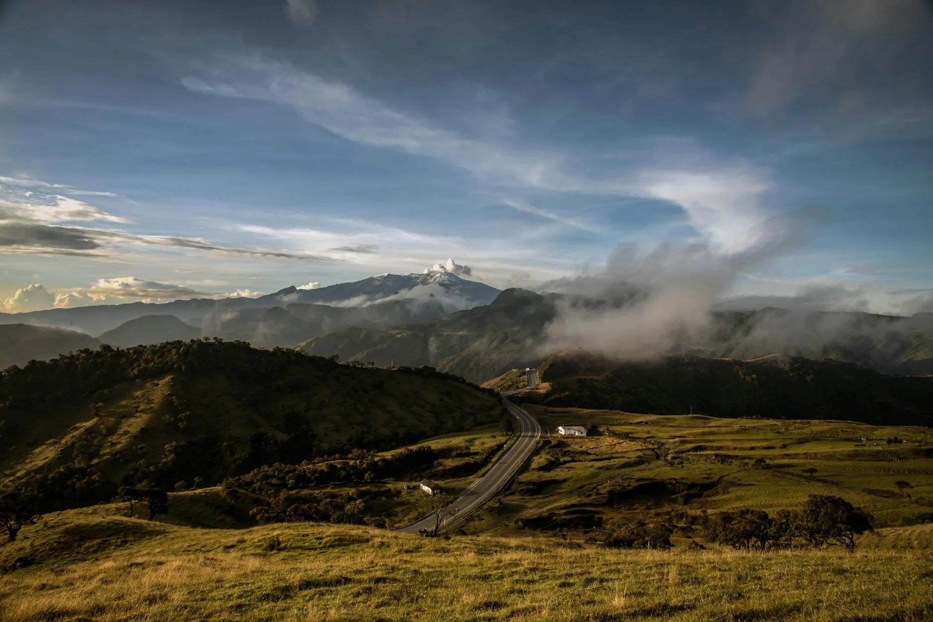 Breathtaking landscape of mountain ranges and valley road in Manizales, Colombia under a clear blue sky.
