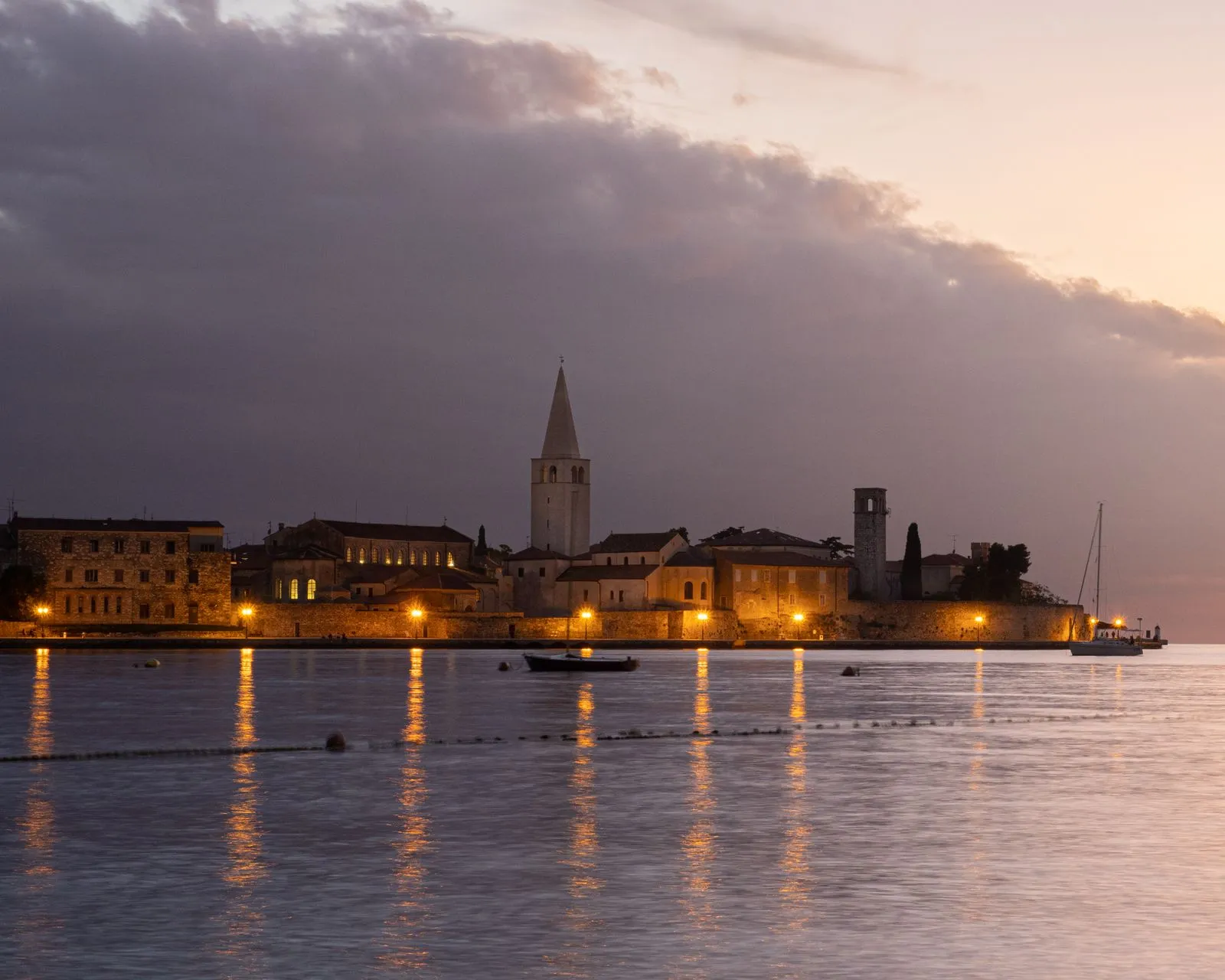 Warm sunset over Croatian coastal town with church spire silhouette