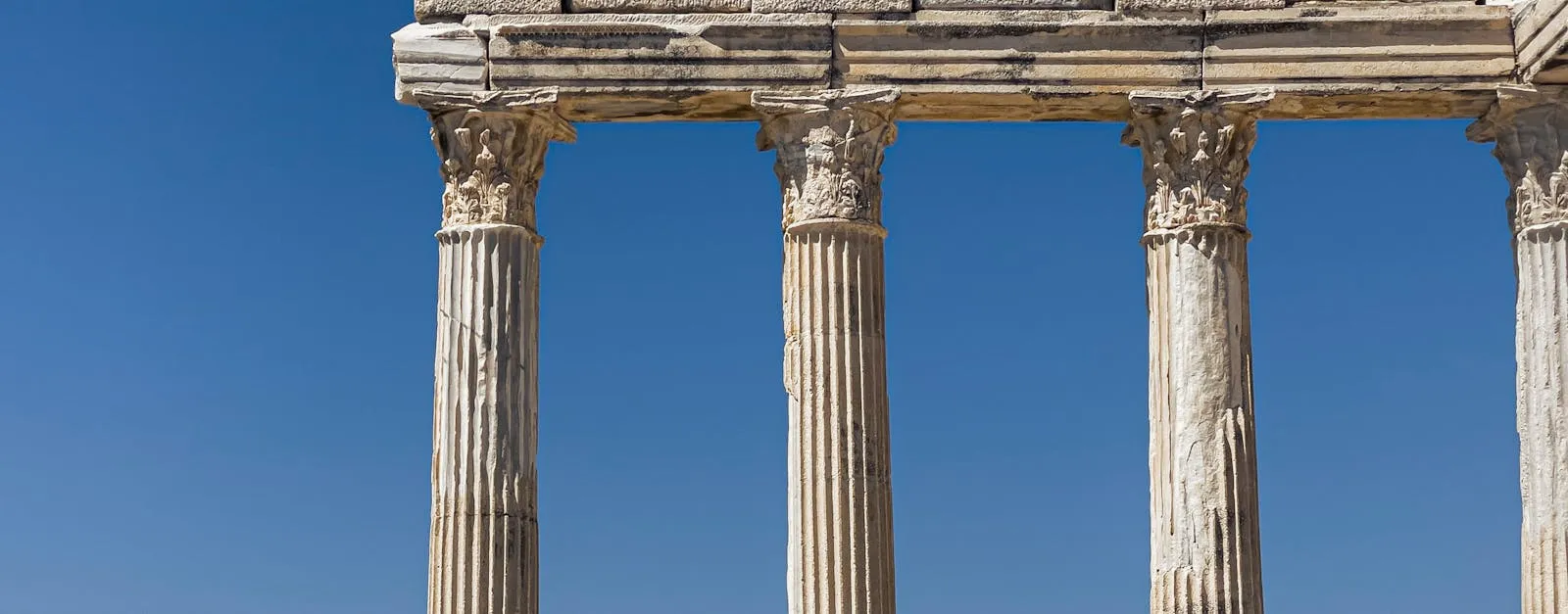 Ancient Greek temple columns against a clear blue sky