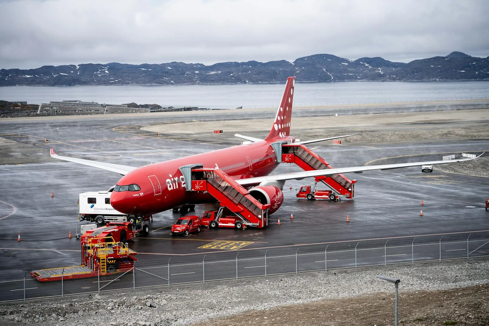 Small propeller aircraft on a runway in Greenland with mountains behind