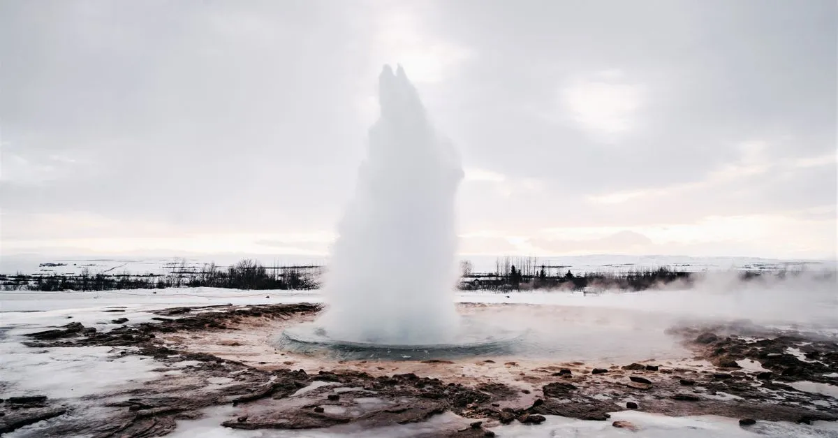 Strokkur geyser erupting against a snowy Icelandic landscape