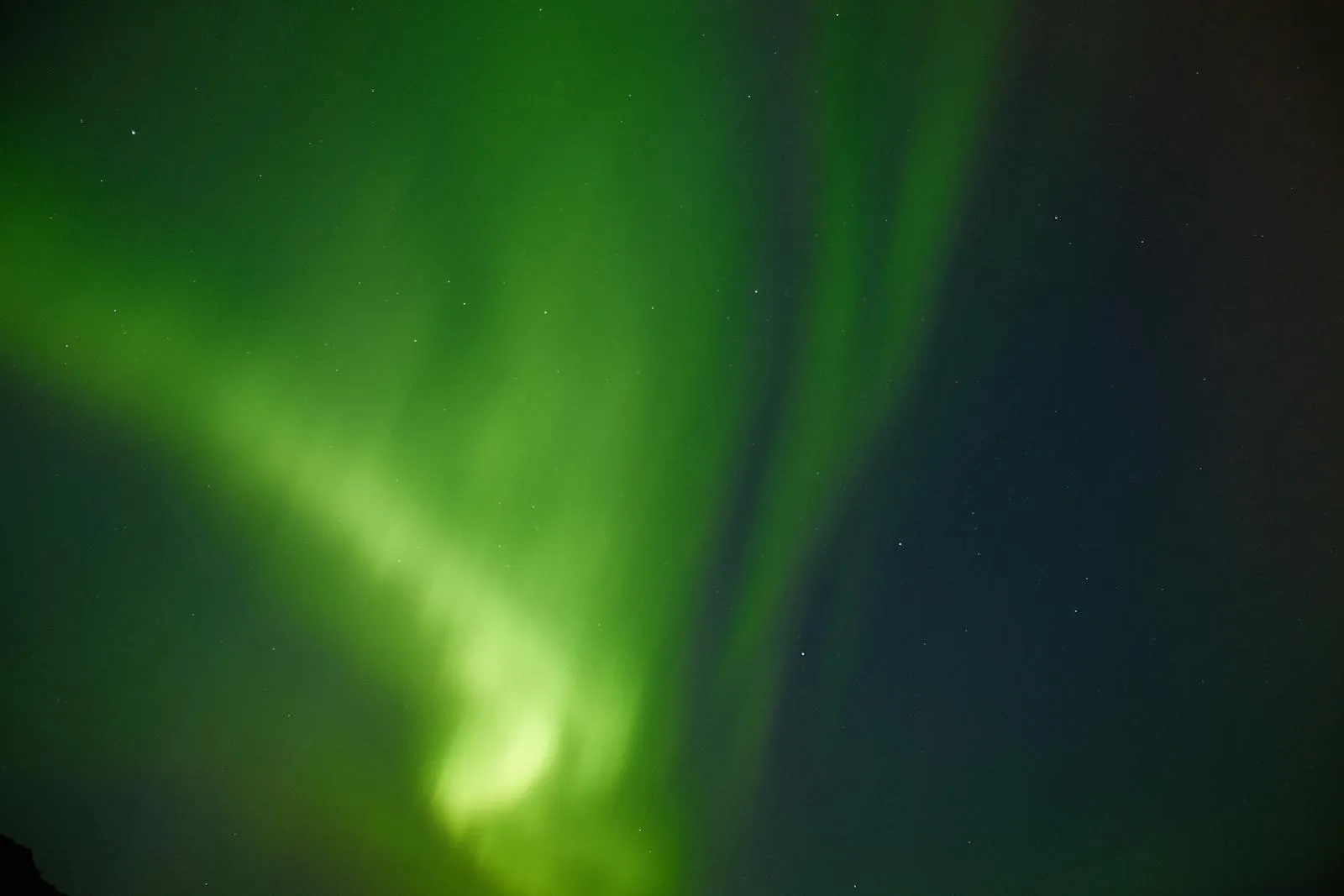 Northern lights dancing in green and purple above an Icelandic landscape