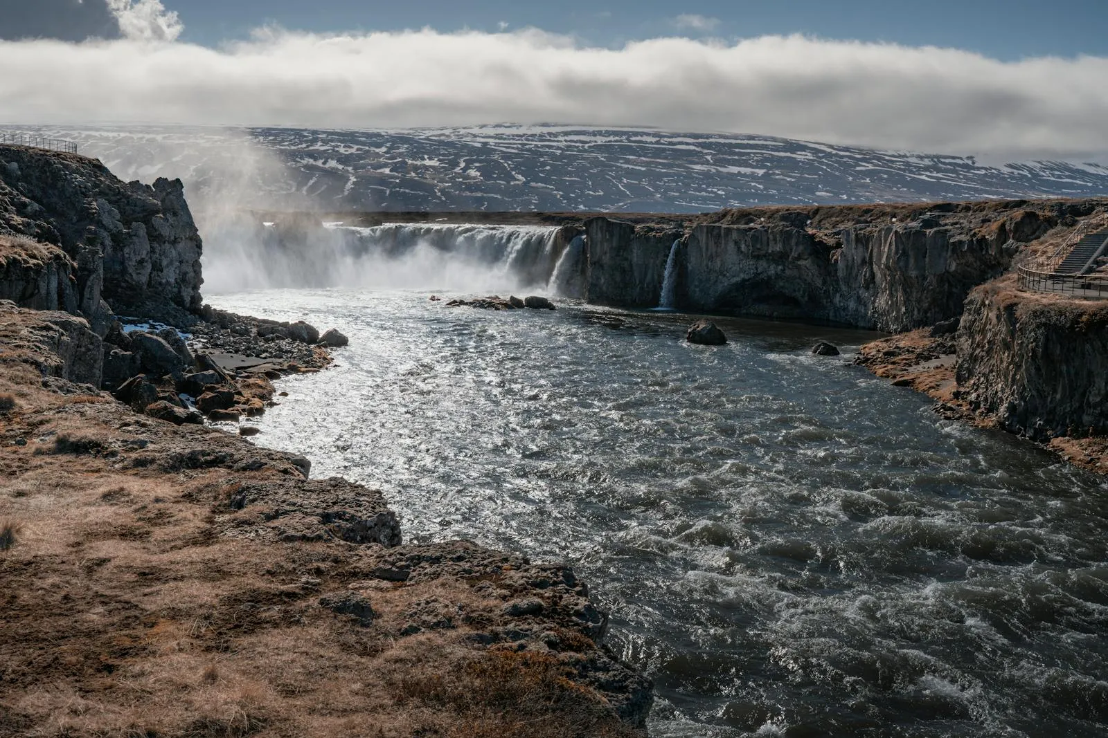 Majestic Icelandic waterfall surrounded by green moss-covered cliffs in summer