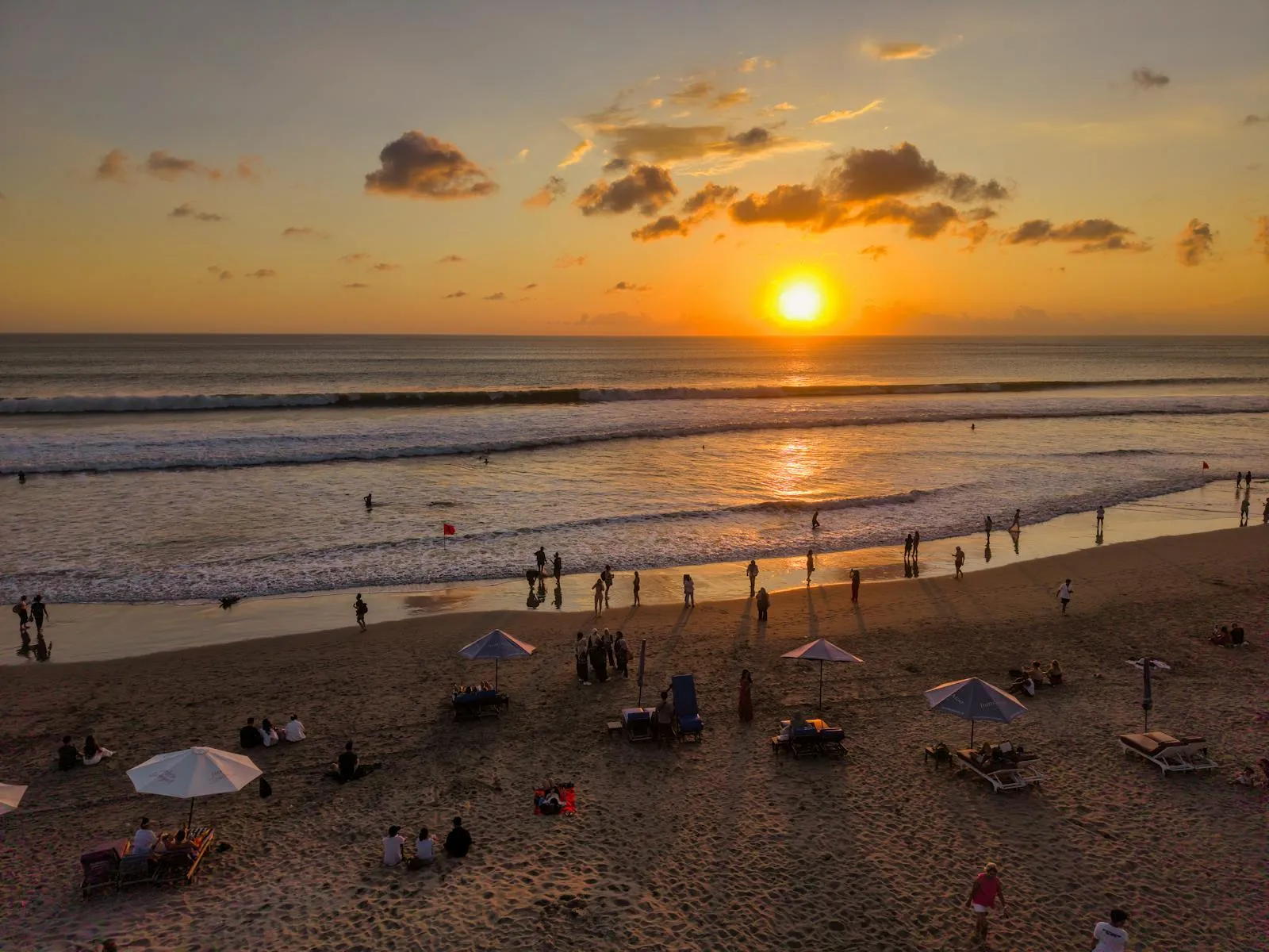 People enjoying a vibrant sunset at Kuta Beach, Bali. Perfect for travel and leisure themes.