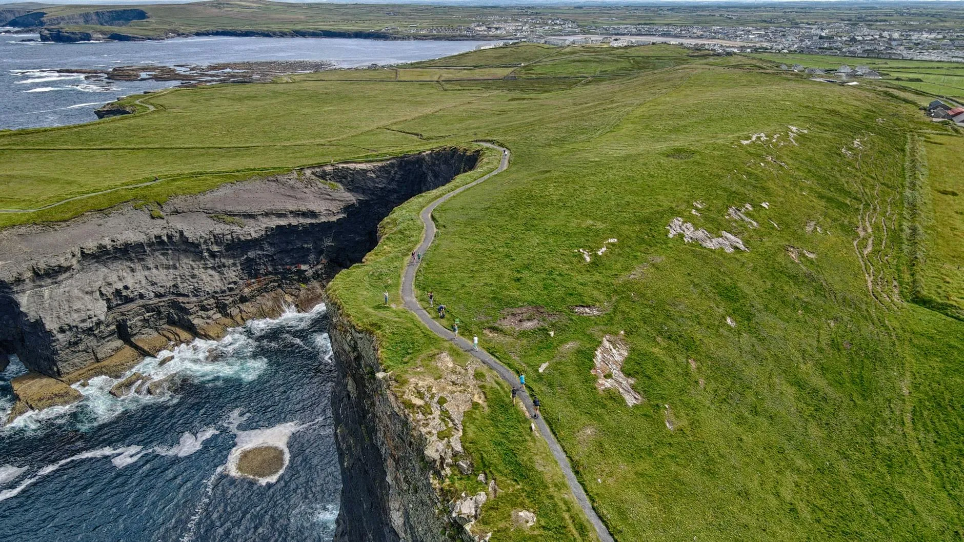Hiker on a cliff path along the Irish coast with ocean views stretching to the horizon