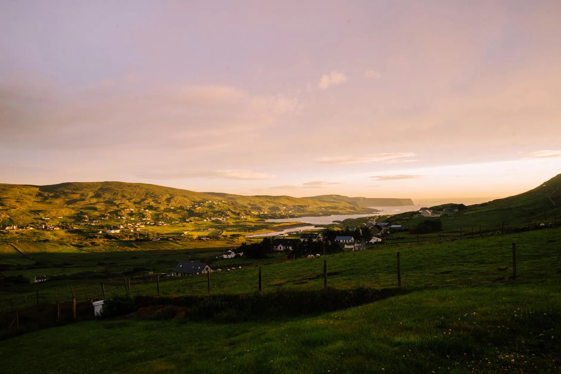 Remote cottage on a hillside overlooking a quiet Irish bay at golden hour