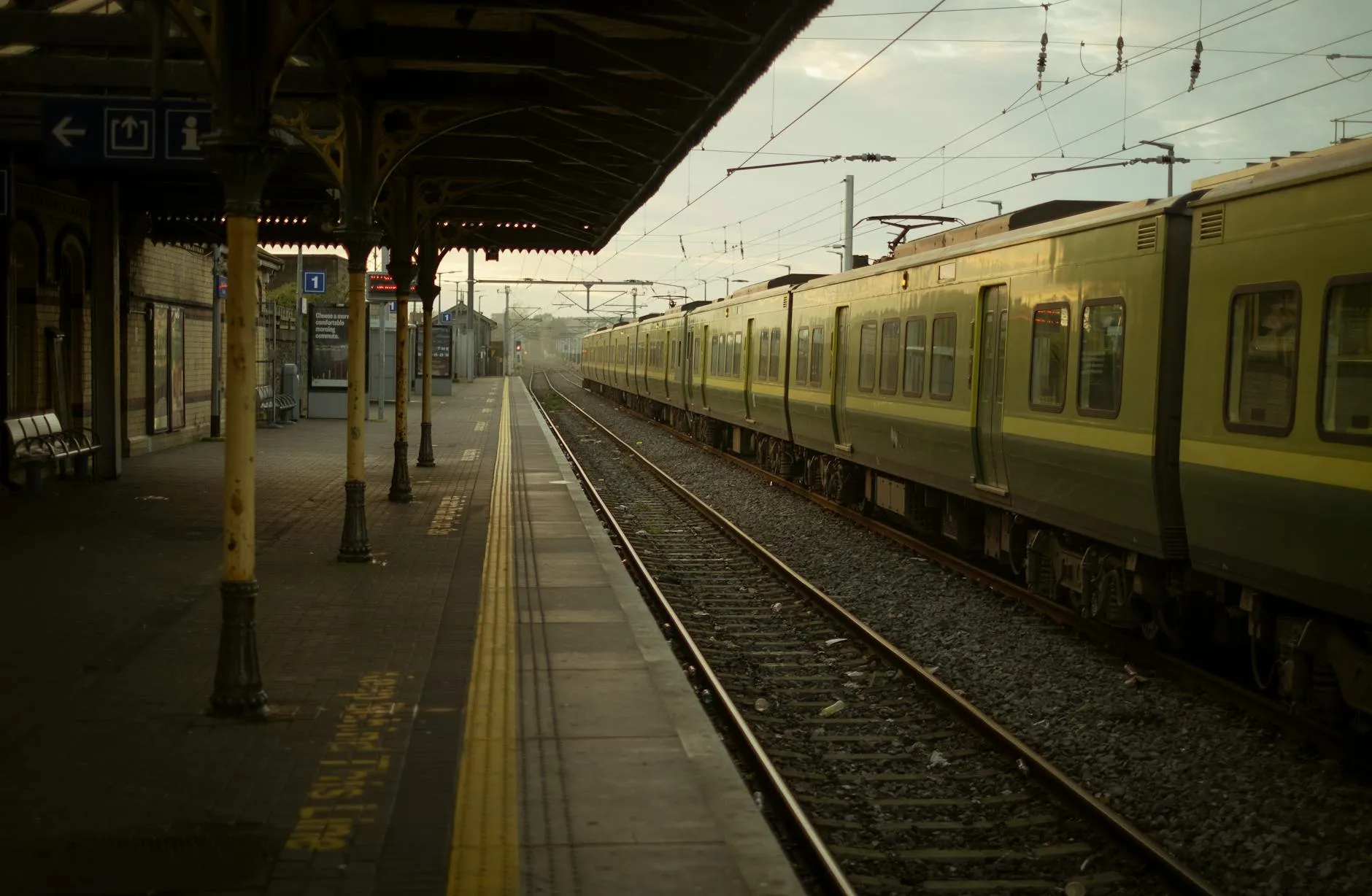 Colourful Irish Rail train at a rural station platform with green hills behind