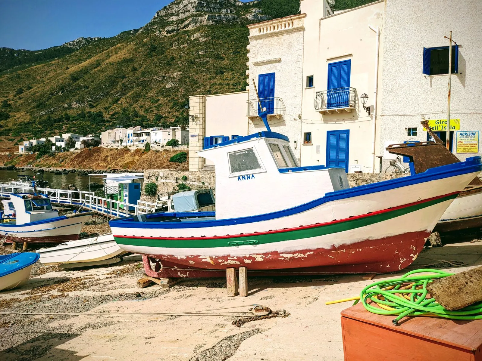 Colourful boats in a Sicilian fishing harbour with baroque church in the background