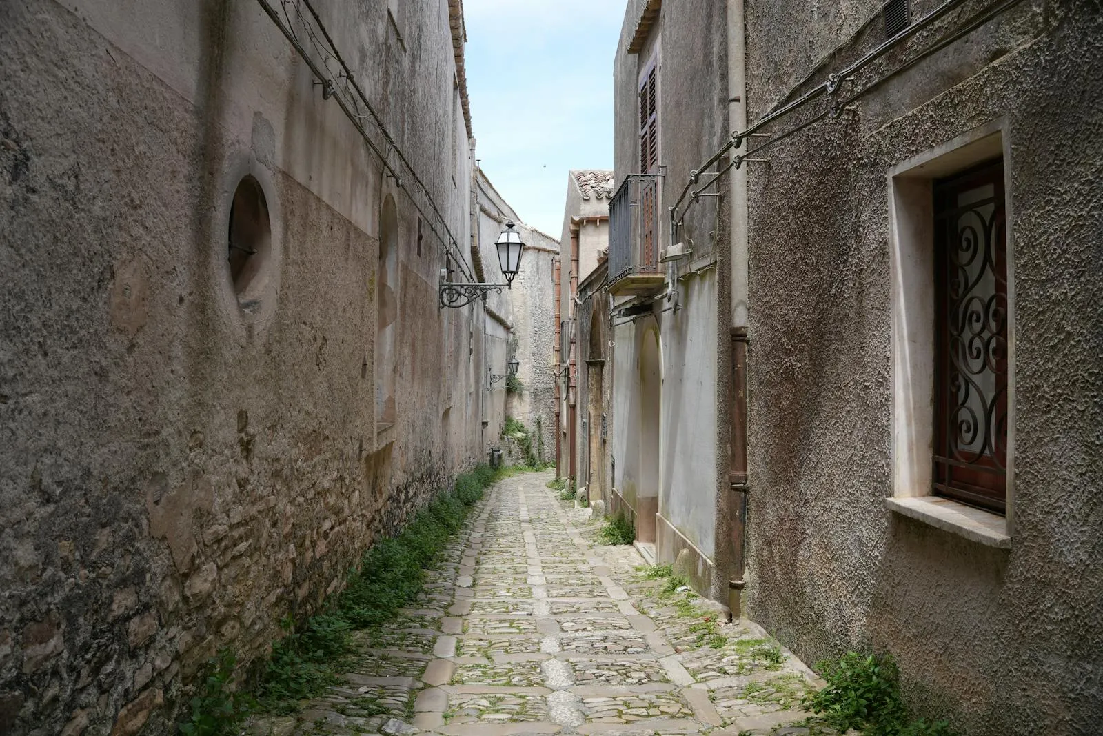 Narrow cobblestone alley in a southern Italian town with hanging laundry