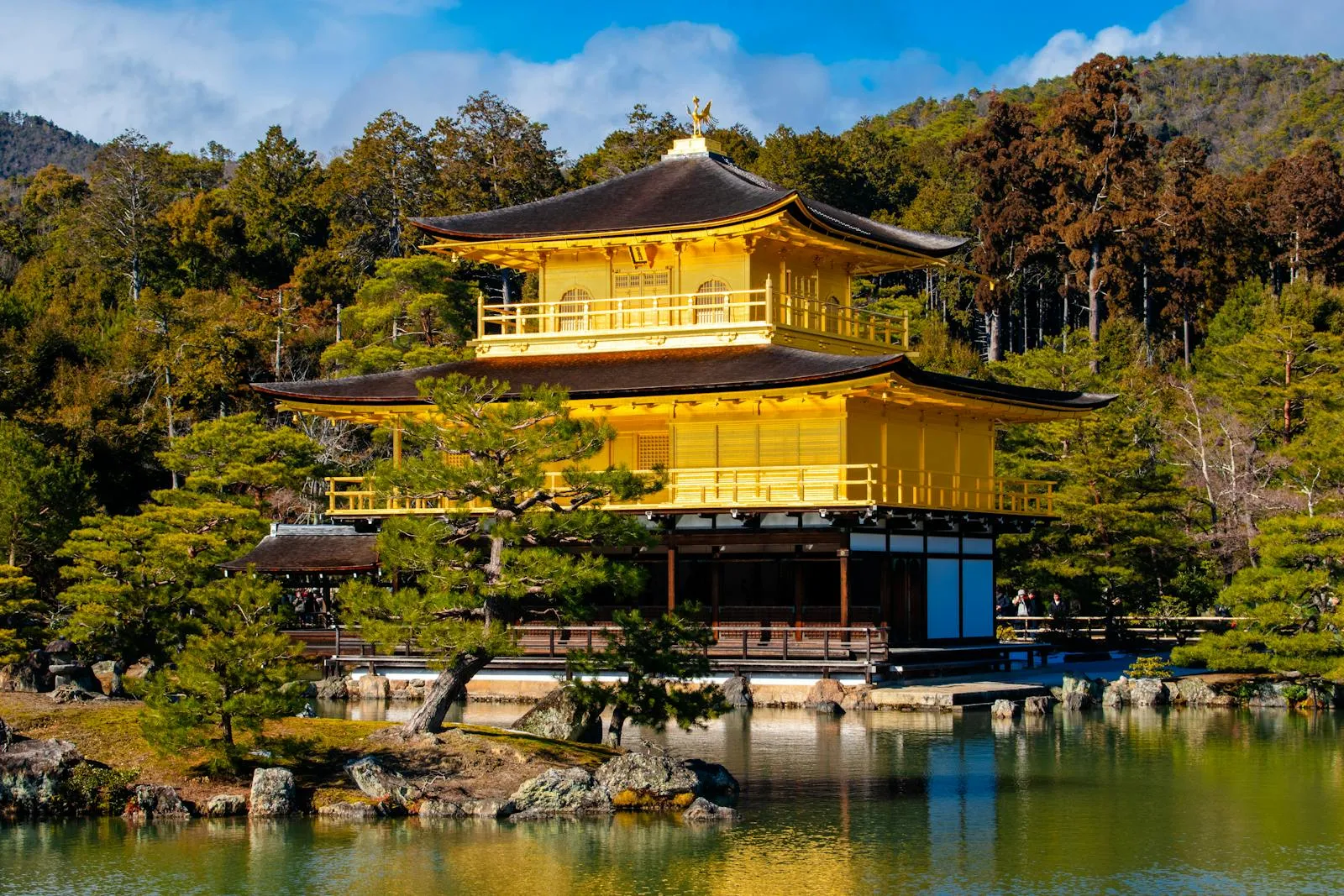 Scenic view of the iconic Kinkaku-ji Temple surrounded by lush greenery and reflecting in the tranquil pond.