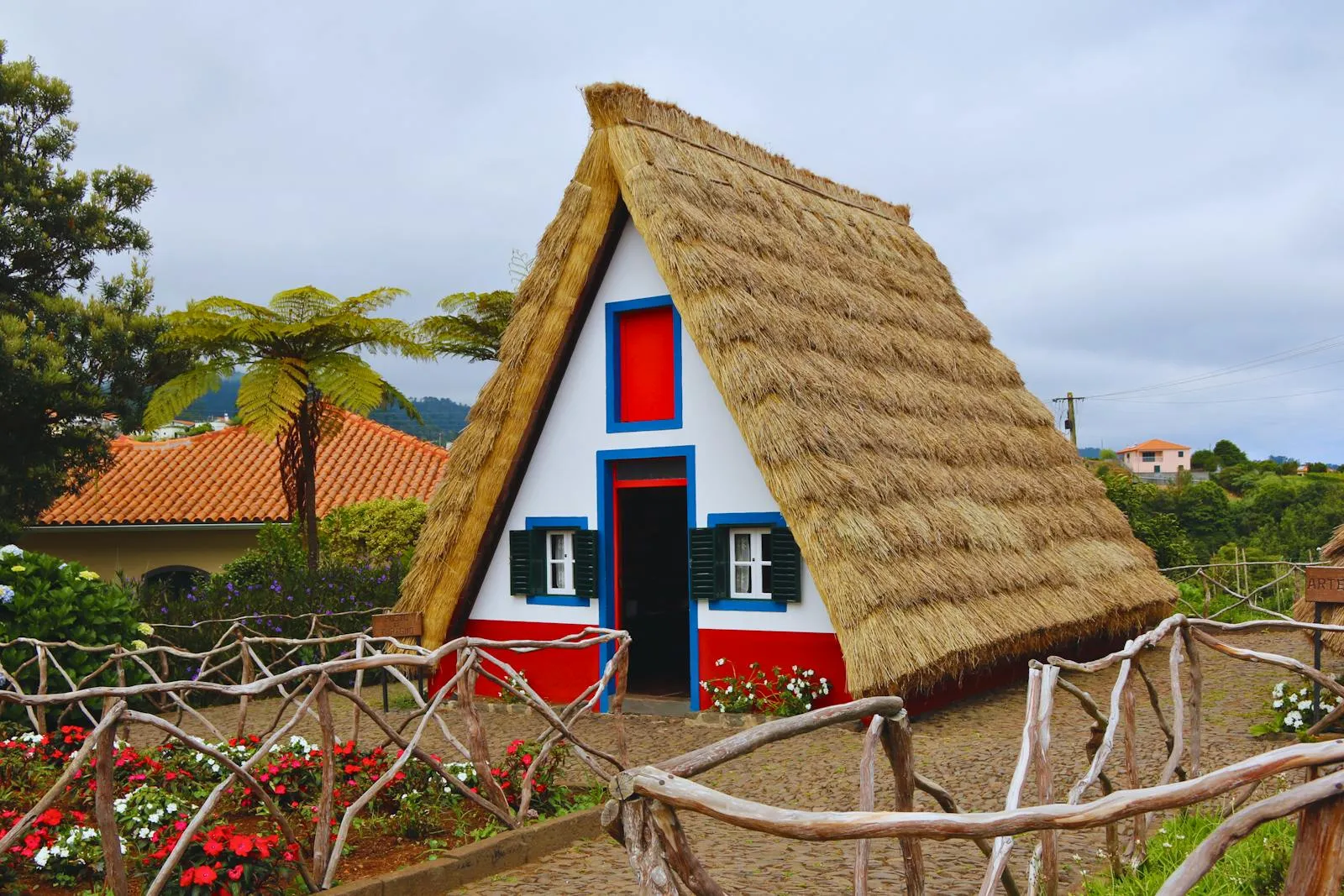 Traditional Santana A-frame houses with thatched roofs surrounded by colourful gardens