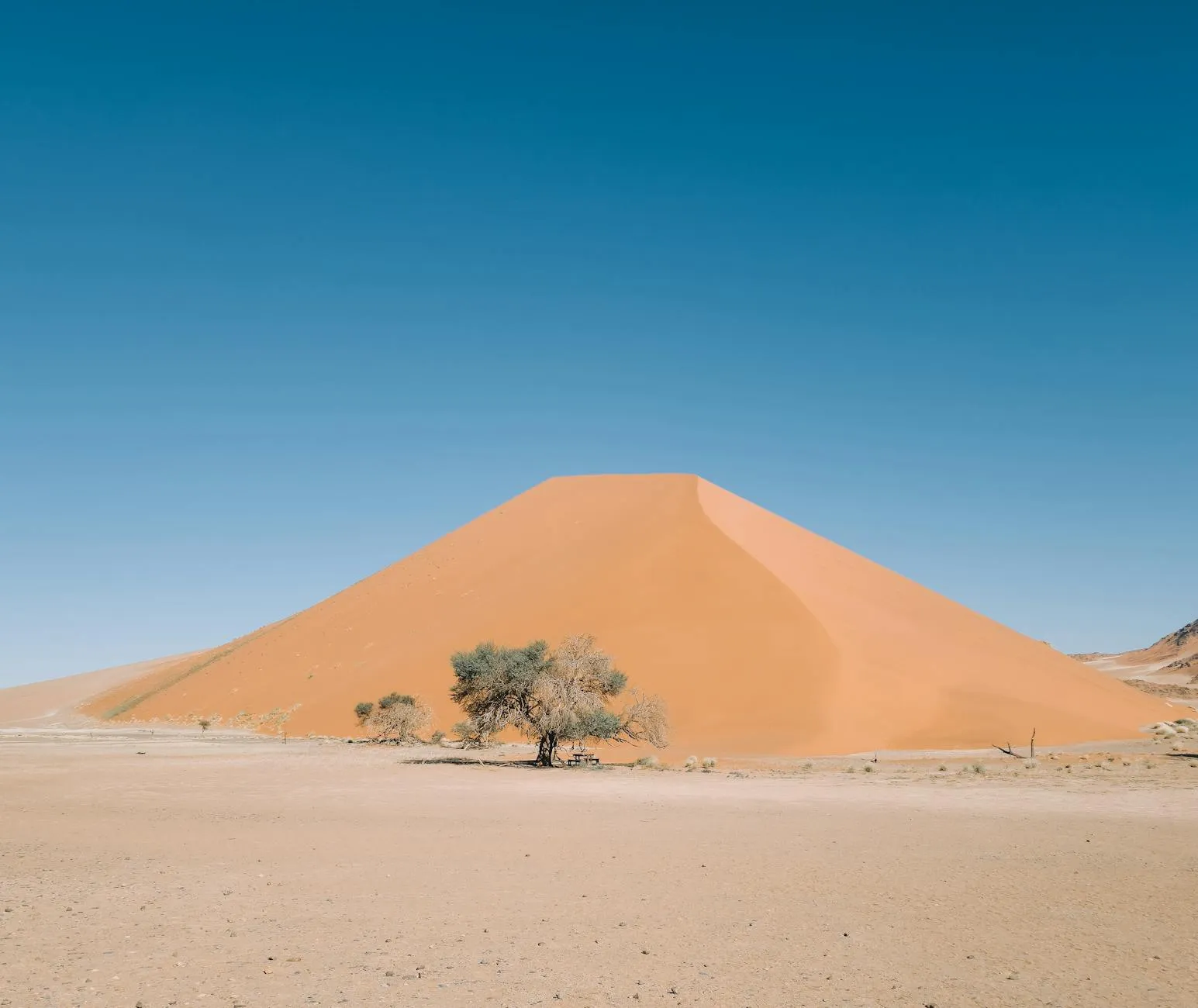 A stunning view of a large sand dune in Sossusvlei under a clear blue sky.
