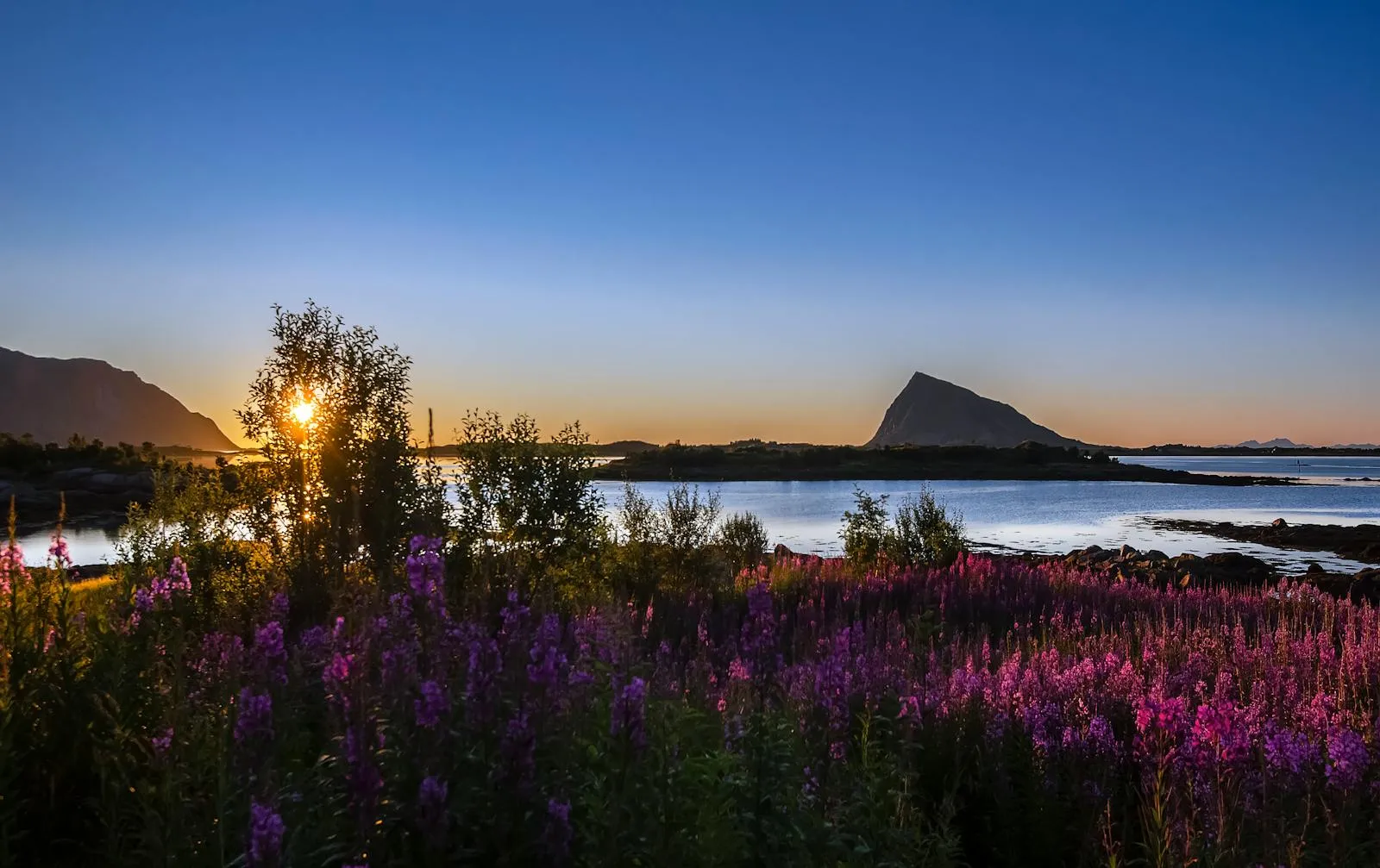 Midnight sun over a calm Norwegian fjord with mountains