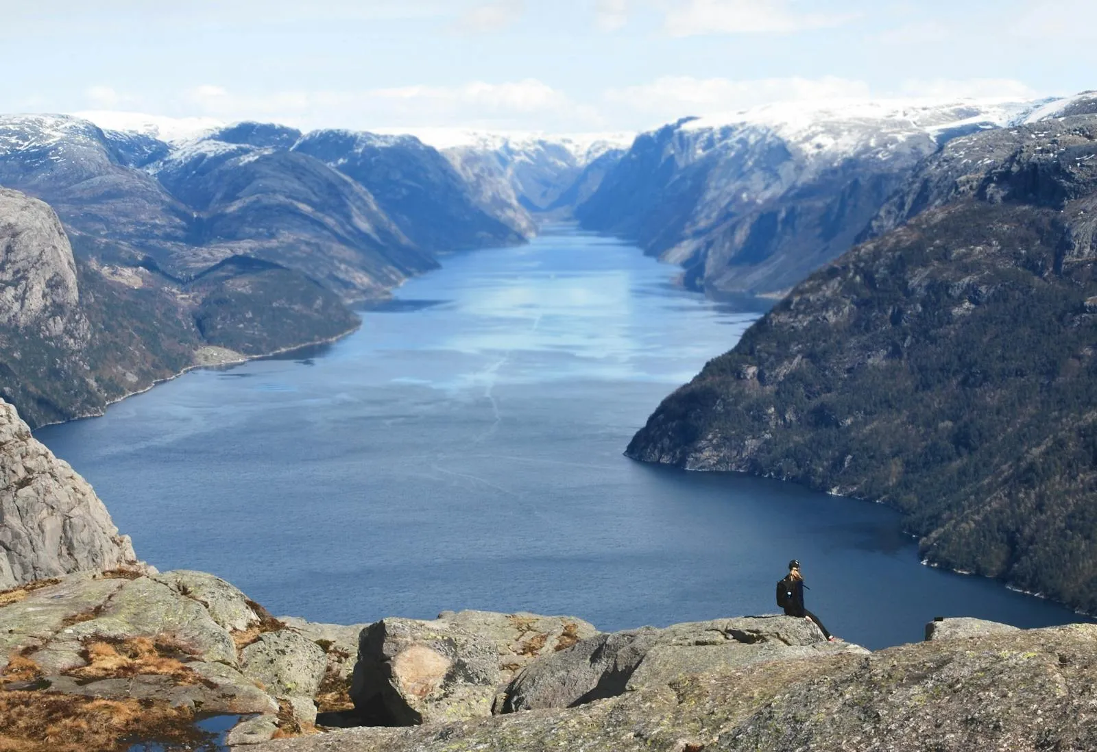 Hiker on a mountain ridge trail above Norwegian fjord