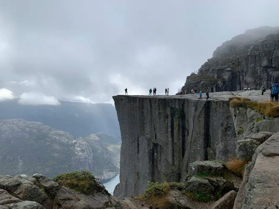 Hikers standing on the flat top of Preikestolen cliff above Lysefjord