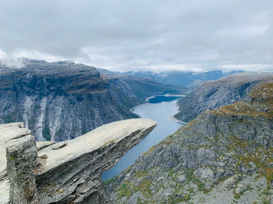 Hiker standing on Trolltunga rock tongue with vast lake below