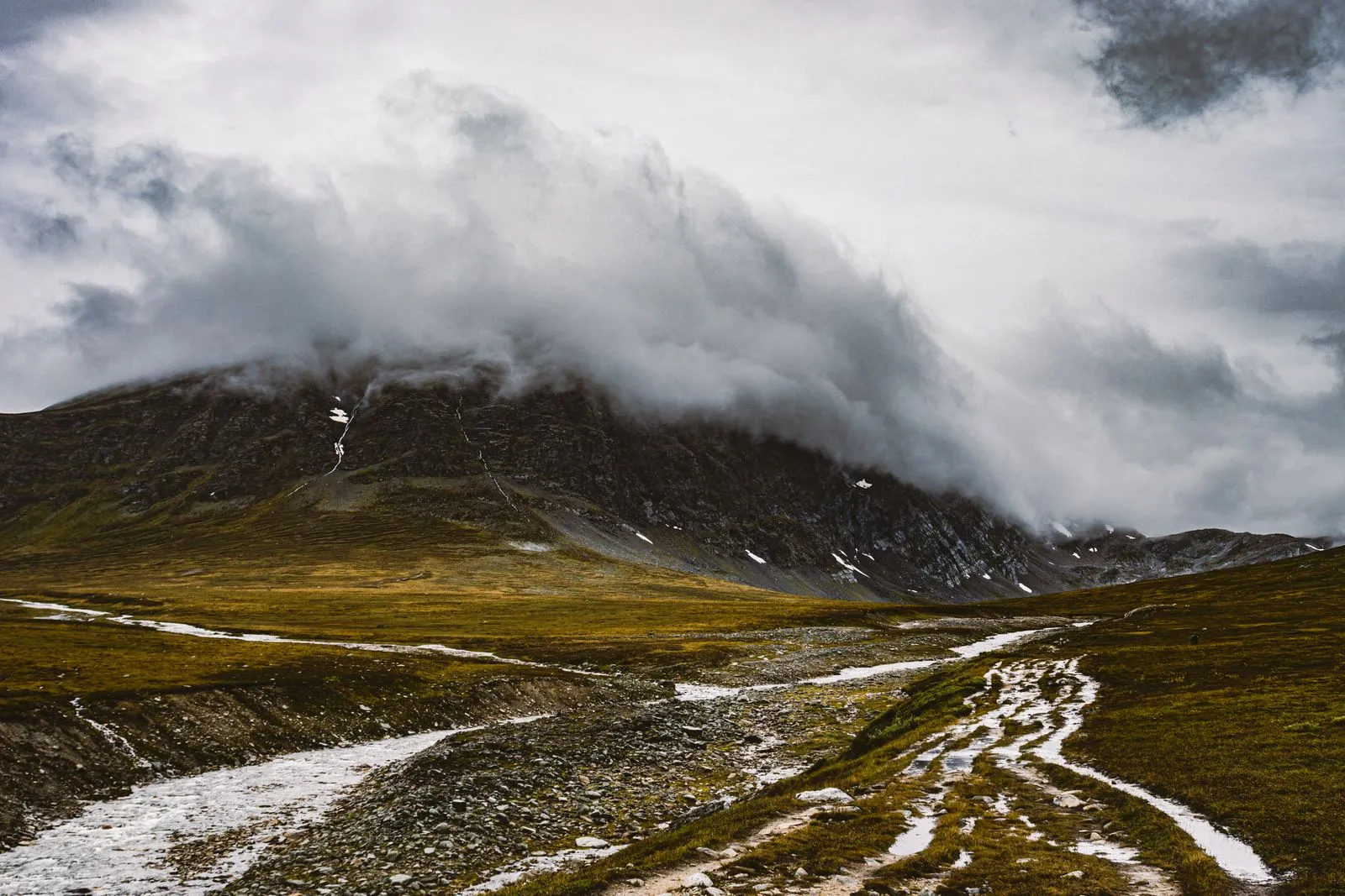 Mountain trail in Norway with dramatic sky and hikers in distance