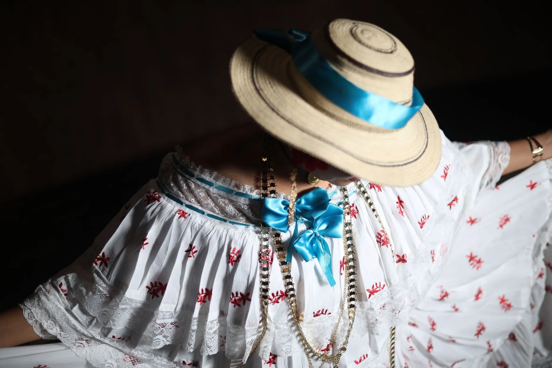 A close-up of a traditional pollera dress adorned with a straw hat and vibrant blue ribbon, showcasing cultural elegance.