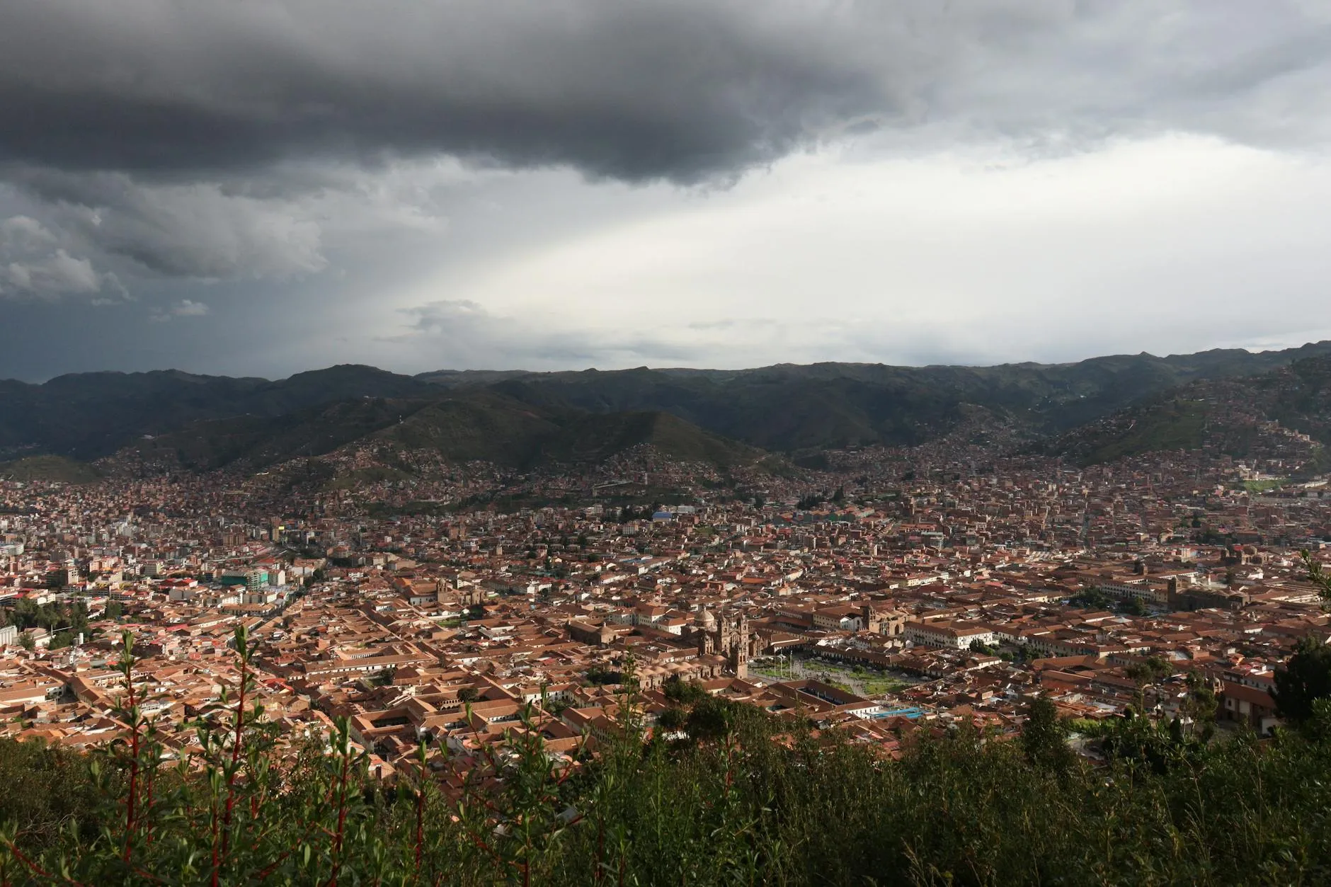 Panoramic shot of Cusco, Peru under dramatic skies, showcasing the city's vast expanse and beautiful architecture.