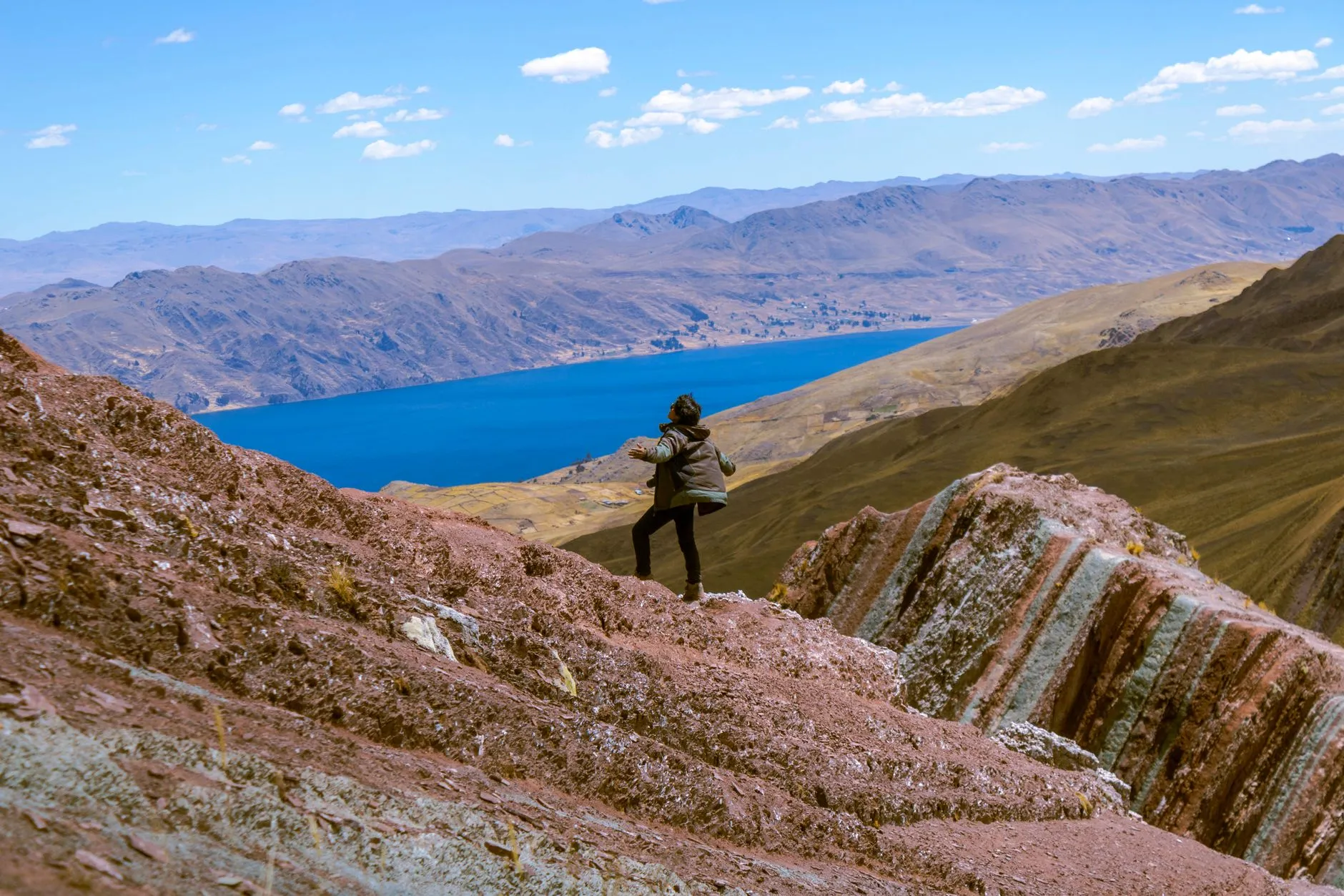 Hiker explores stunning mountain landscape near Layo, Cuzco with vibrant lake and rugged terrain.