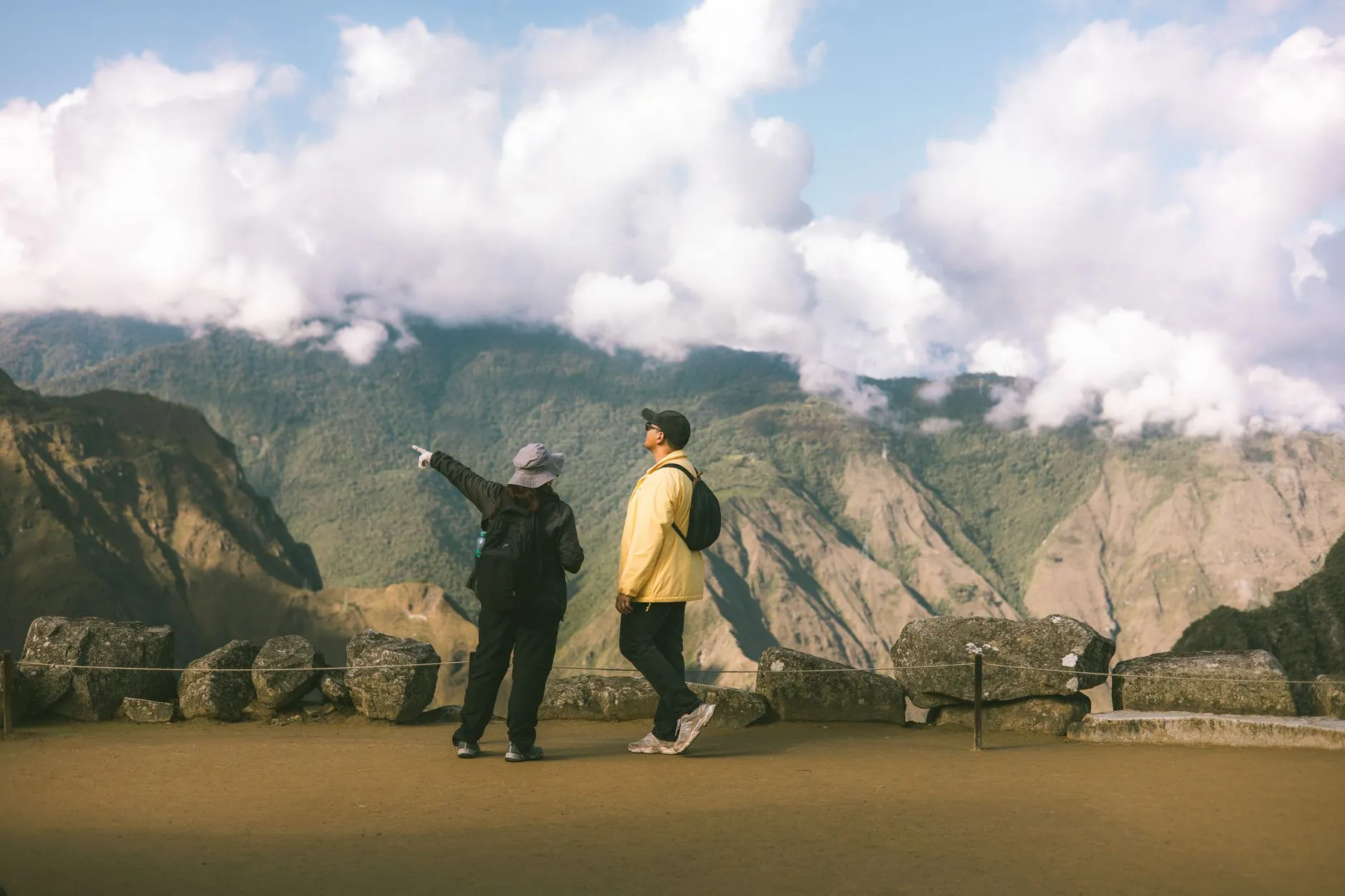 Two tourists admire the breathtaking landscape of Machu Picchu, Peru, under a cloudy sky.
