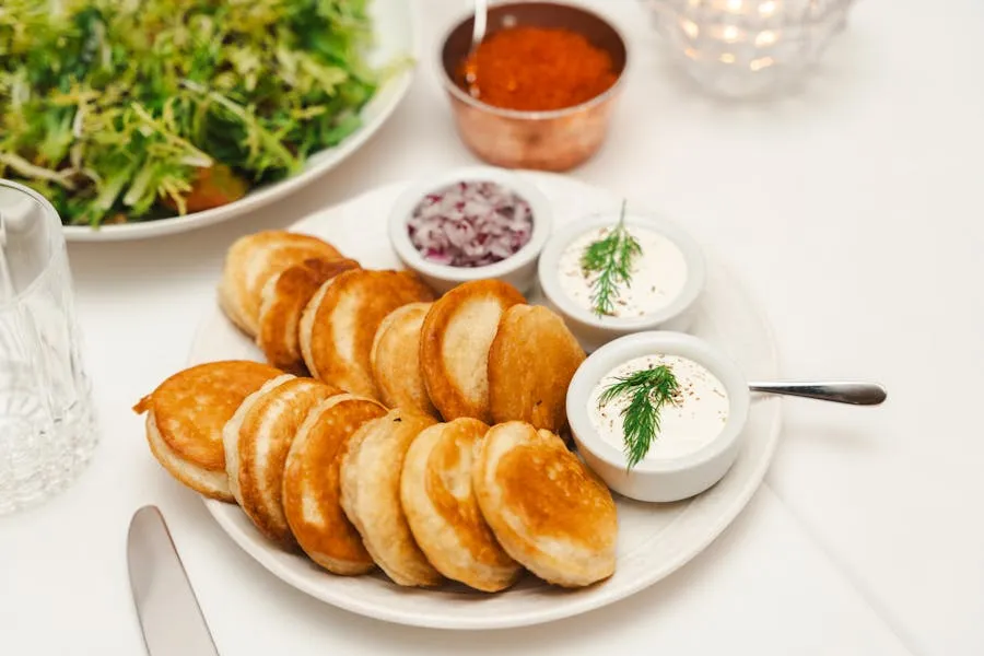 Stack of golden blini pancakes topped with red caviar and dill