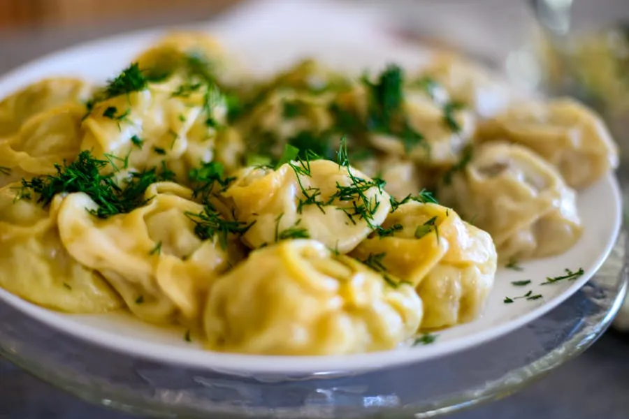 Plate of pelmeni dumplings with sour cream and fresh herbs