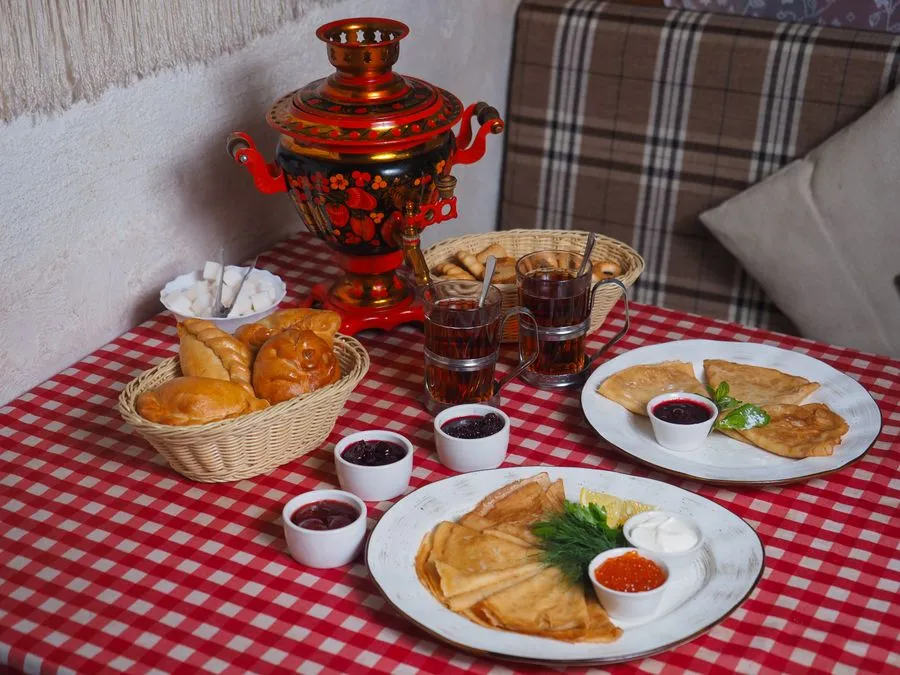 Russian samovar with ornate design pouring tea into a traditional glass