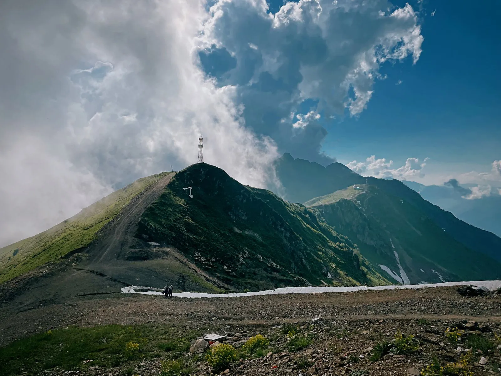 Hikers on a mountain trail in the Caucasus with dramatic peaks and valleys