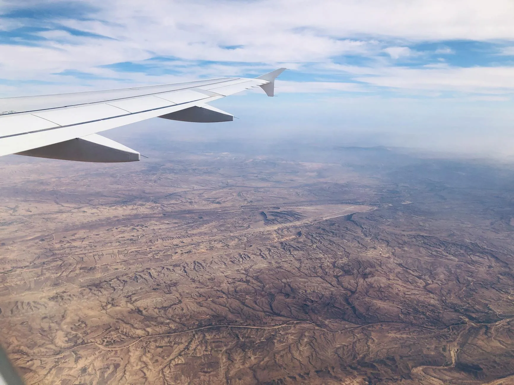Domestic aircraft flying over Saudi desert landscape with mountains in distance