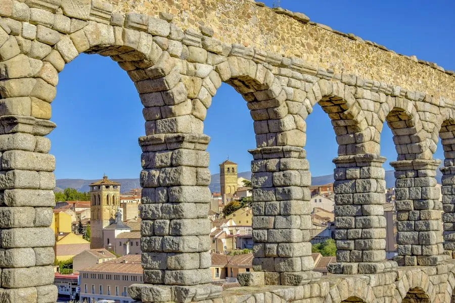 Roman aqueduct of Segovia with monumental stone arches against a blue sky