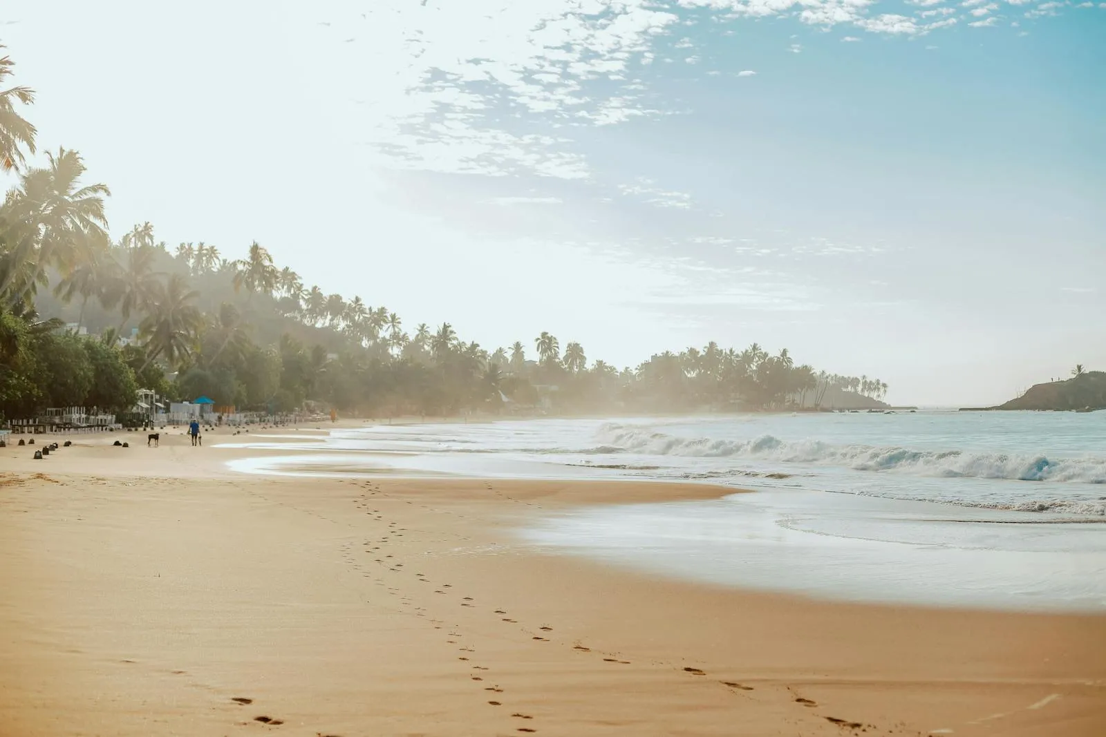 Footprints in the sand on a tranquil beach in Mirissa, Sri Lanka at sunrise.