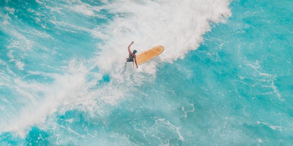 Aerial shot of surfers mastering waves in clear blue ocean