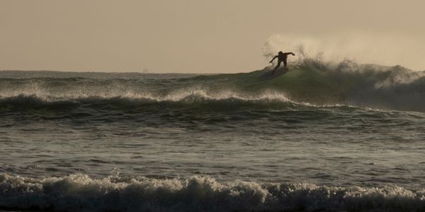 Surfer catching waves during sunrise at Sunshine Coast, Australia
