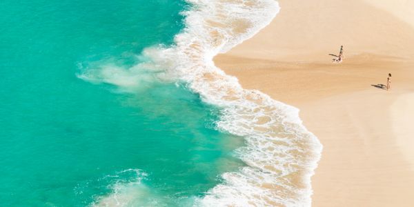 Aerial shot of surfers mastering waves in clear blue ocean