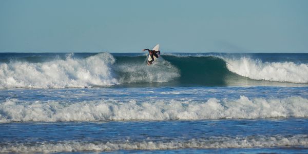 Dynamic aerial maneuver by surfer on beach waves
