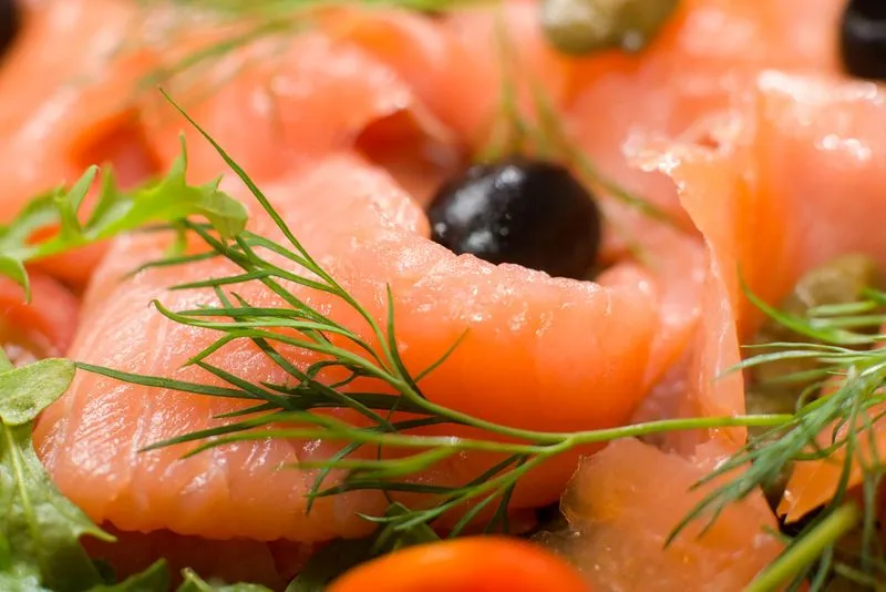 Sliced gravad lax with mustard-dill sauce on a serving board