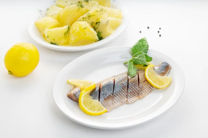 Plate of pickled herring with boiled potatoes, sour cream and chives