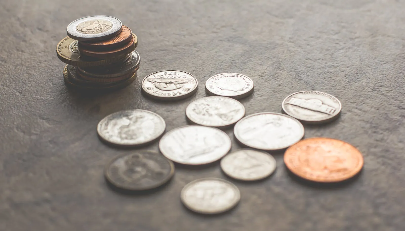 Assorted foreign coins stacked and scattered on a textured surface