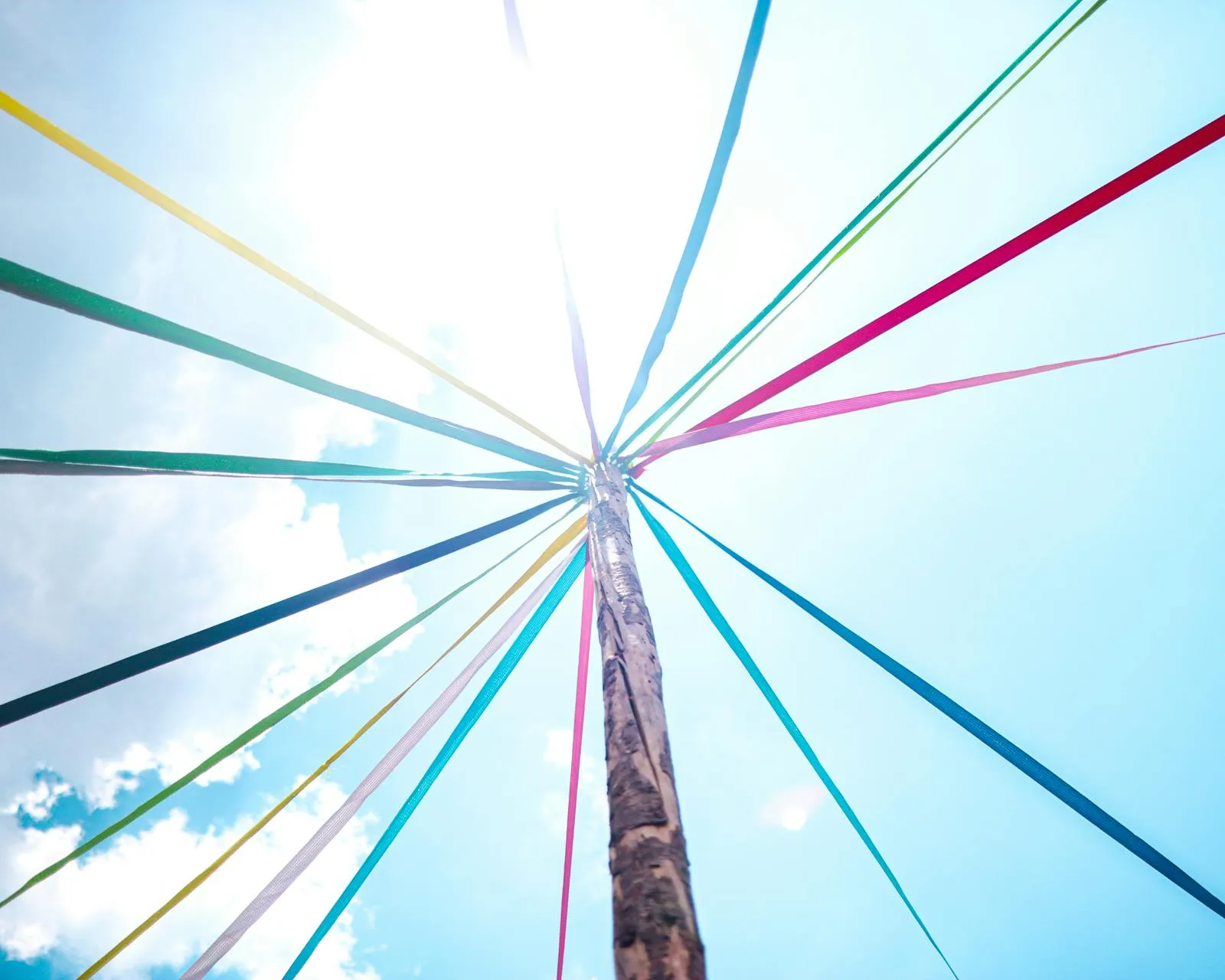 Traditional Swedish midsummer maypole decorated with flowers and greenery against a blue sky